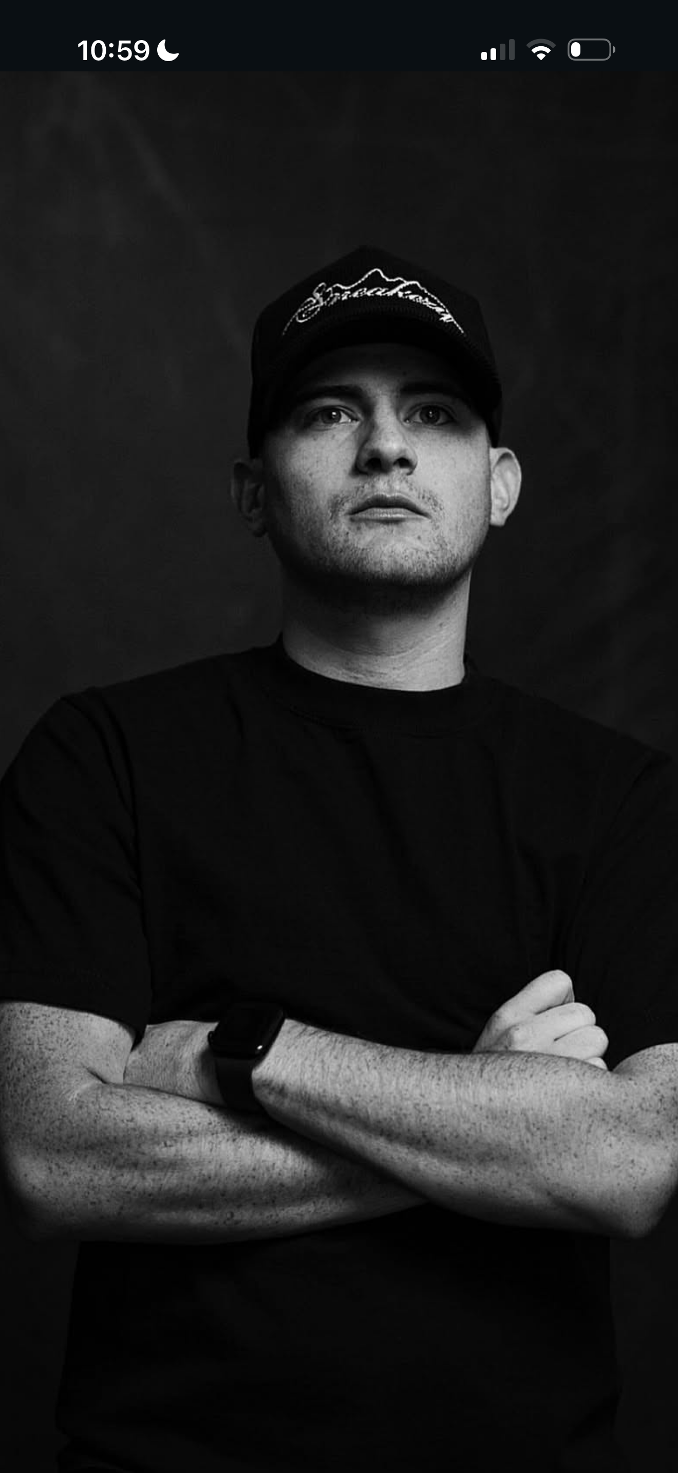 Bryan Sanchez wearing a black cap and shirt with arms crossed