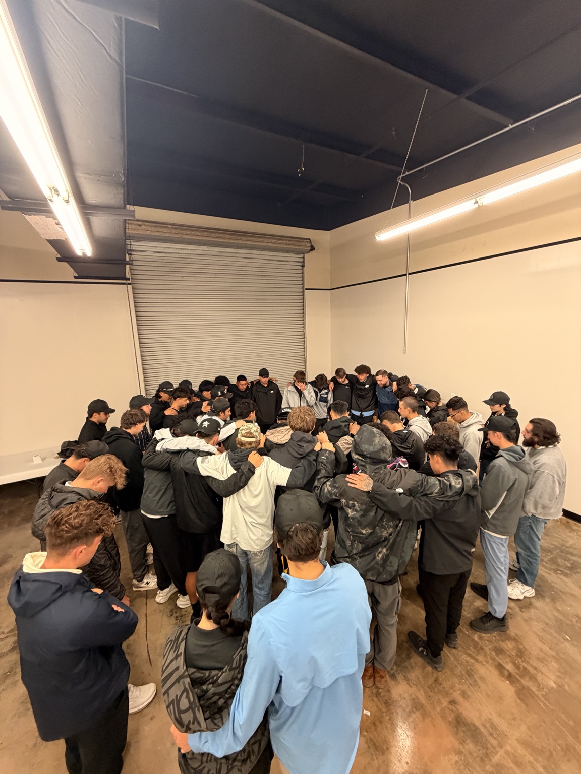 Rally teammates standing together in a circle with arms around each other